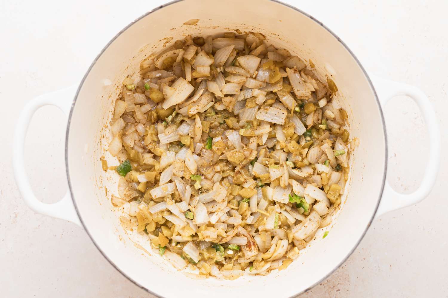 A dutch oven with beans and onions cooking to make white chicken chili recipe.