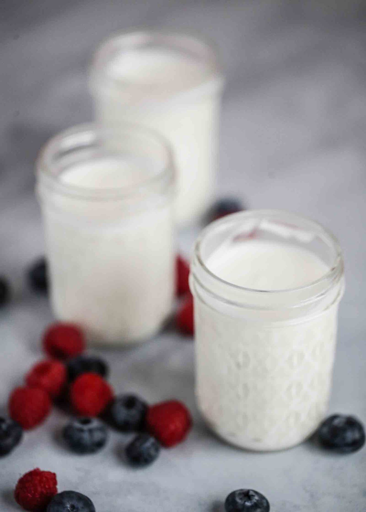 Three jars of yogurt with berries near the jars