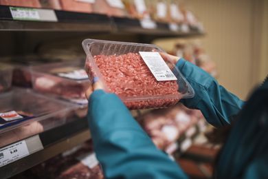 Unrecognisable woman choosing fresh ground beef in supermarket.