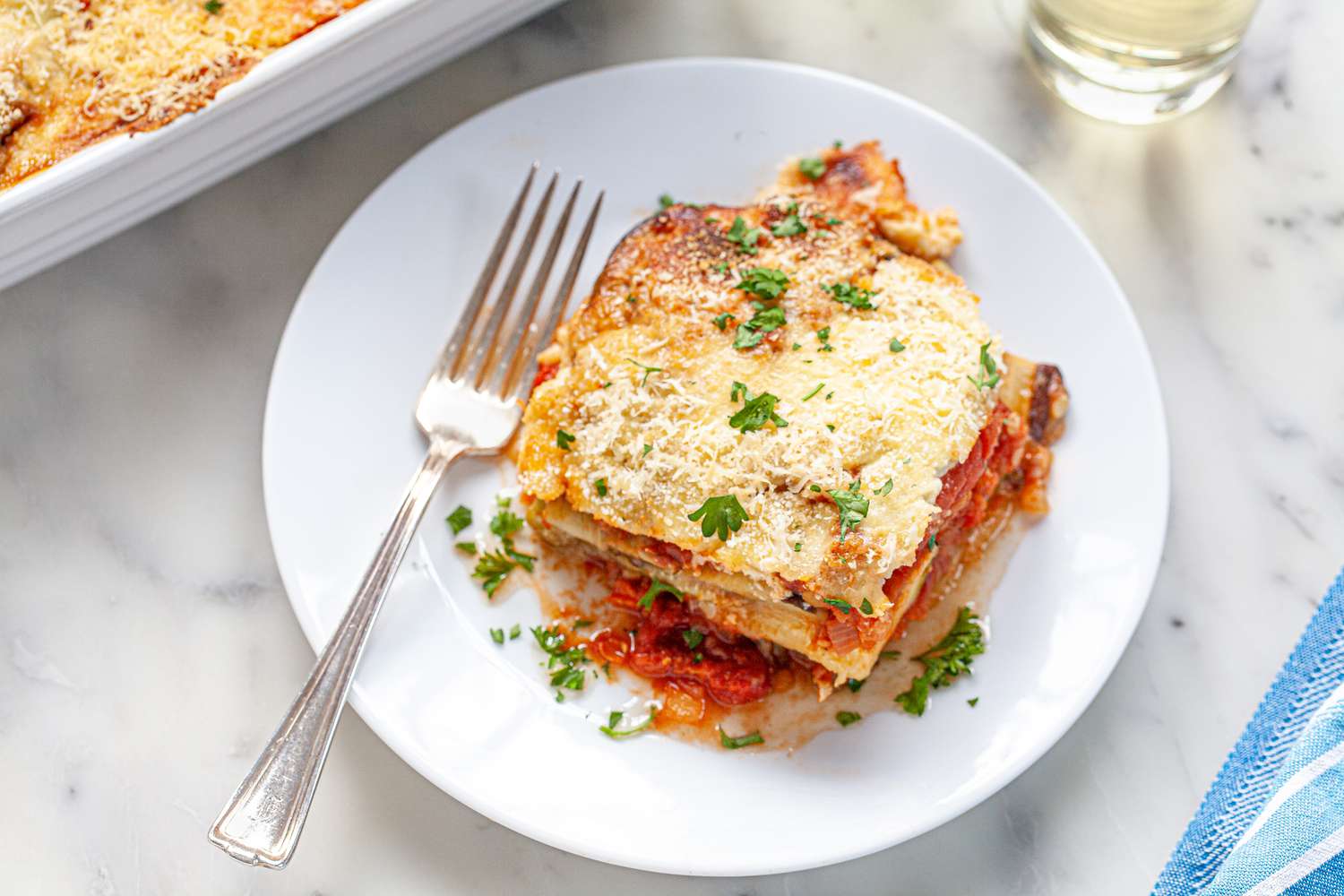 Vegetable moussaka on white plate with fork