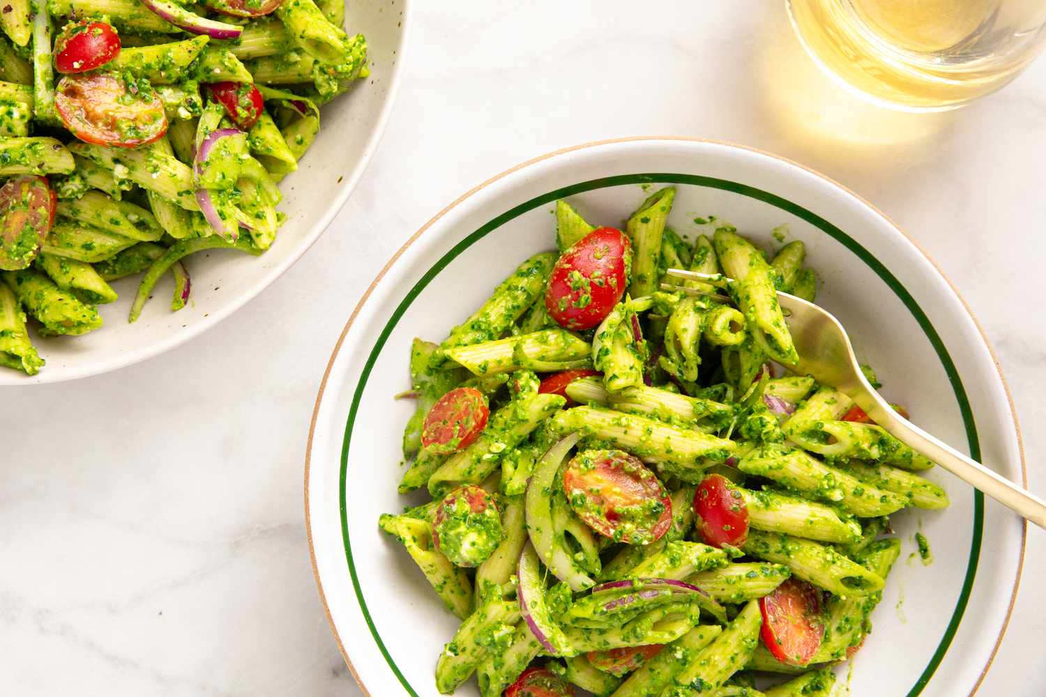 Bowl of pasta with spinach and feta garnished with vegetables