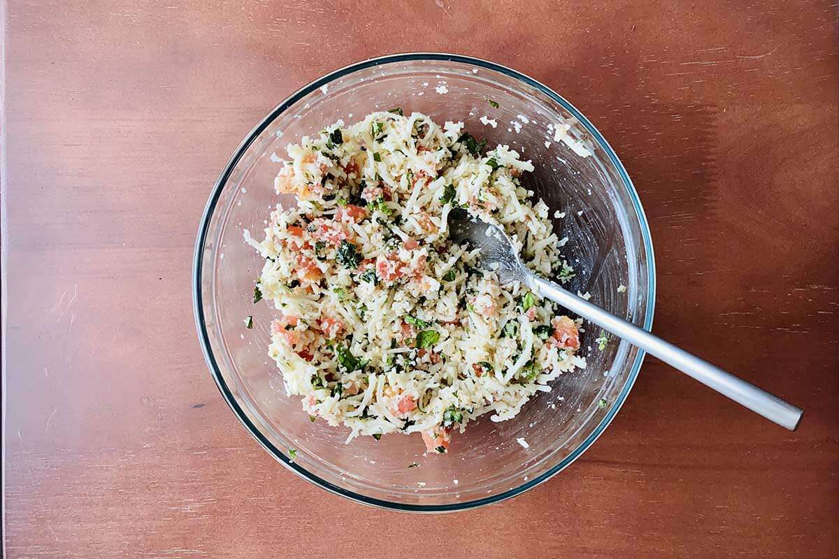 A bowl of cheese and hervs mixed to make cheese and herb stuffed tomatoes.