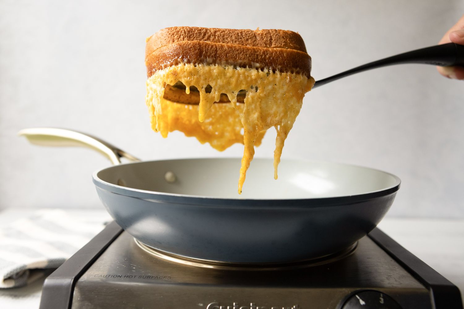 Grilled cheese sandwich being lifted with a spatula from a frying pan on a stovetop