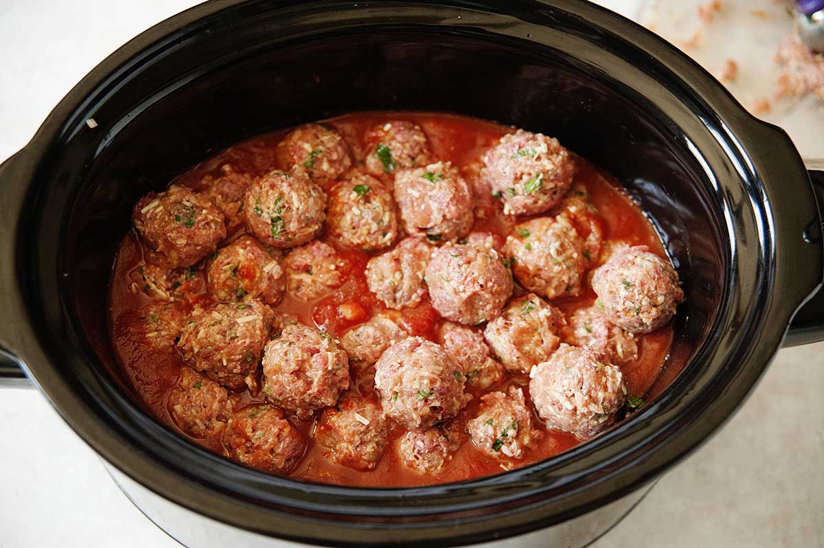 Meatballs in a slow cooker filled with tomato sauce.