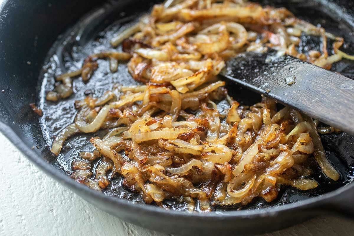 Caramelized onions in a cast iron skillet to make a homemade patty melt.