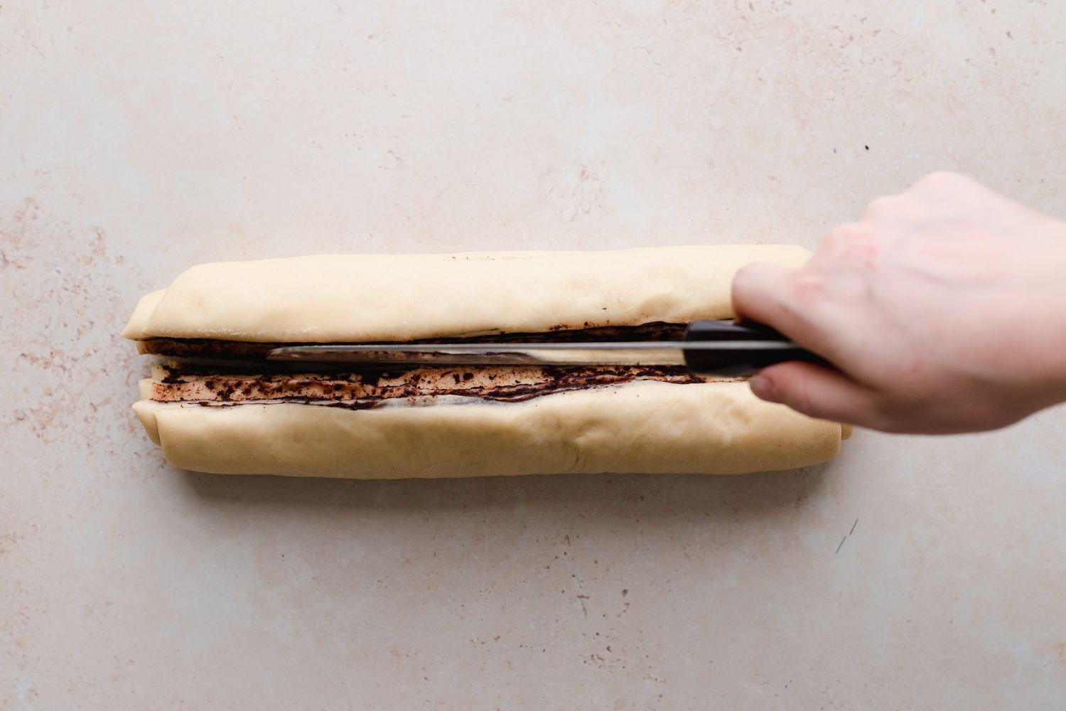 Slicing the rolled dough horizontally to make chocolate babka.