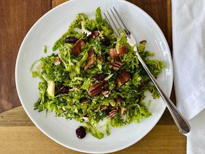 Raw Kale and Shaved Brussels Sprout Salad with Maple Dijon Vinaigrette on a plate with a fork to the right.
