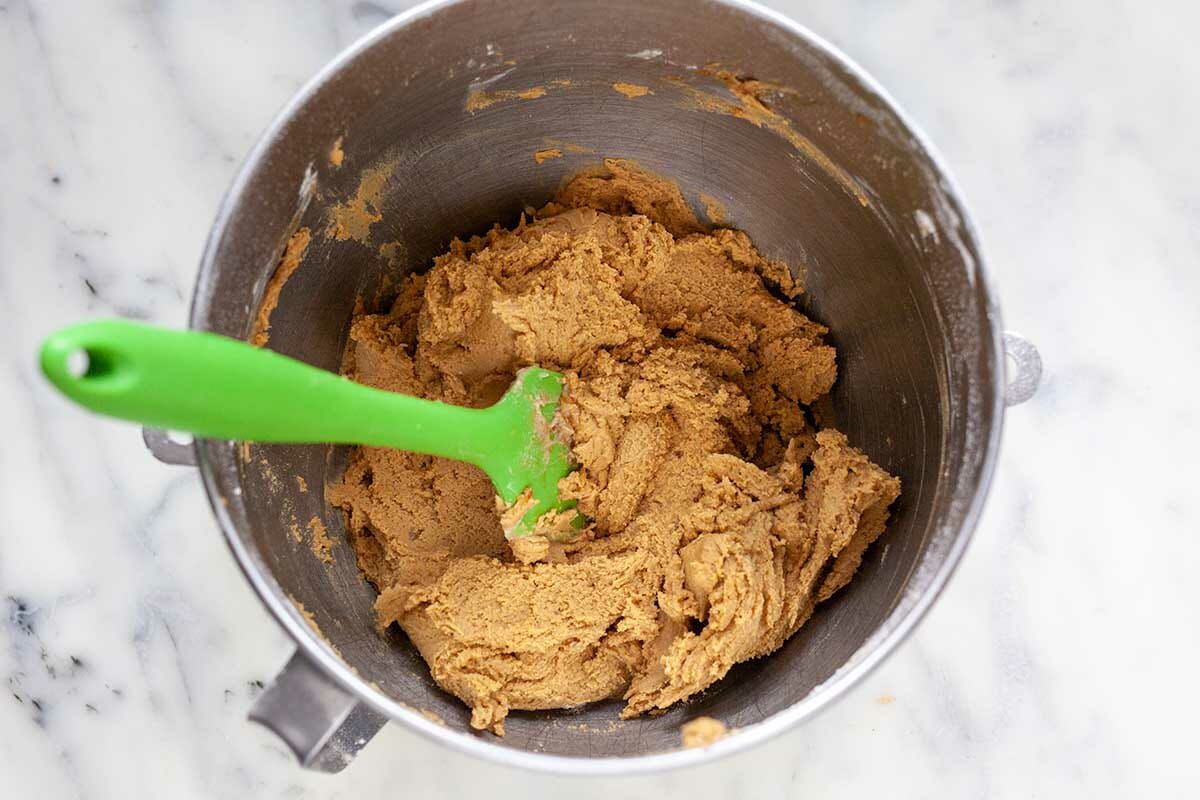 A metal mixing bowl with a flexible spatula mixing dough for Make Ahead Slice and Bake Ginger Cookies.