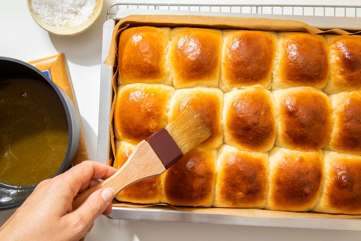 Melted salted honey brushed onto the salted honey rolls using a pastry brush (rolls still in the pan on the cooling rack)