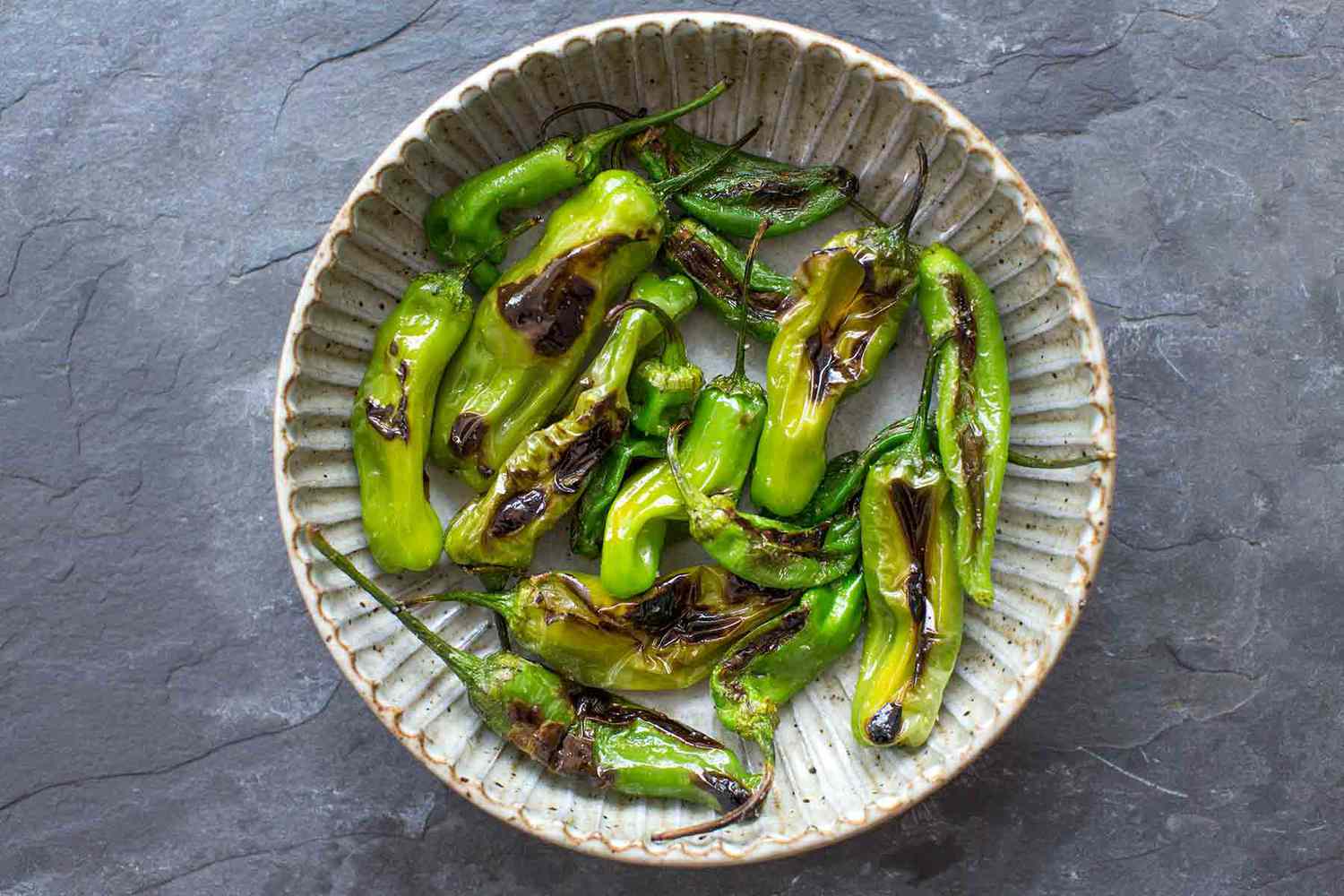 blistered shishito peppers in a bowl