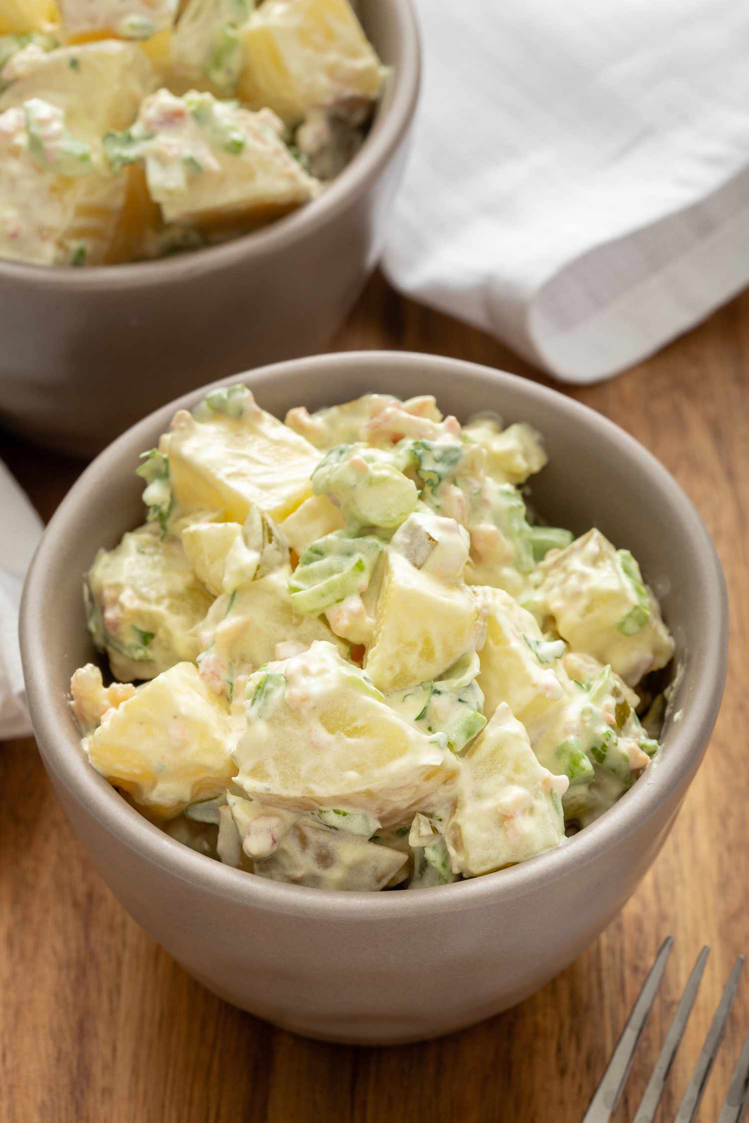 Potato salad in a bowl on a wooden background.