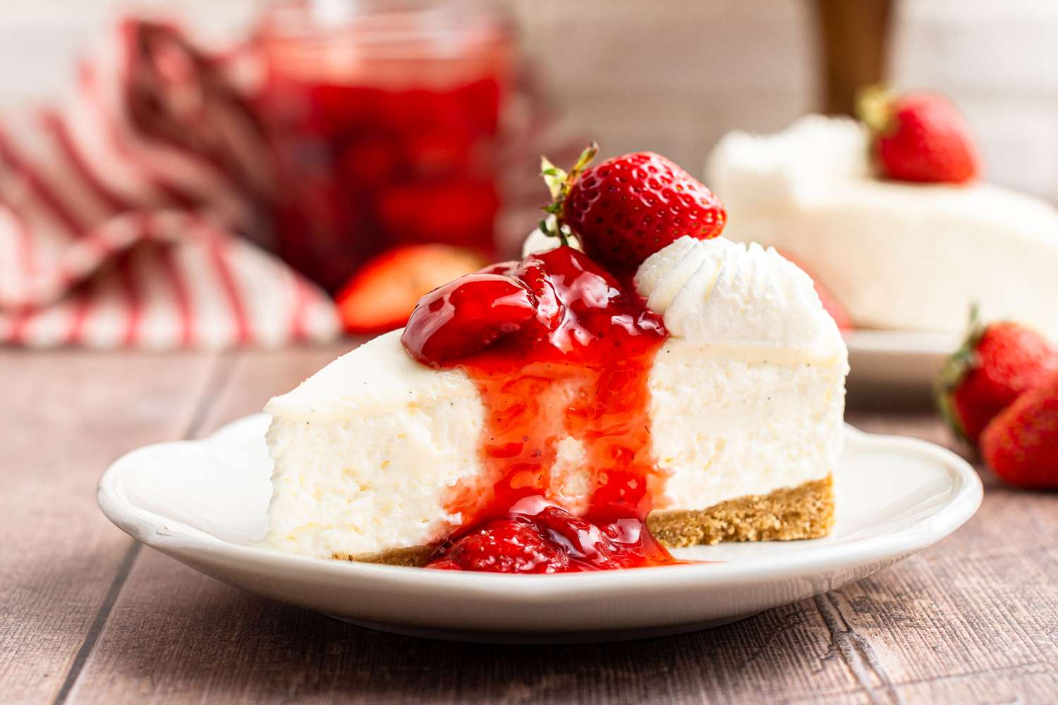 A side view of a plate with easy no bake cheesecake topped with strawberry preserves.