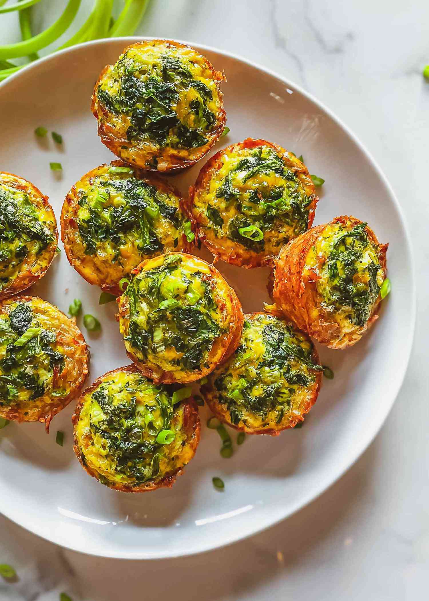 A white plate of muffin hash brown and egg bites set on a marble background.
