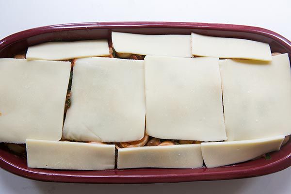 sliced cheese on top of cheese tortellini in baking dish