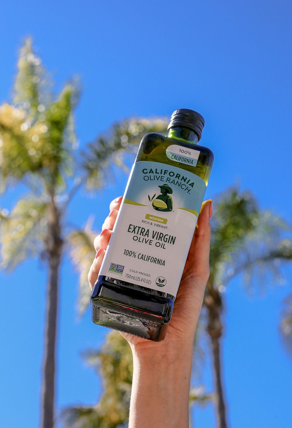 A hand holding a bottle of California Olive Ranch olive oil