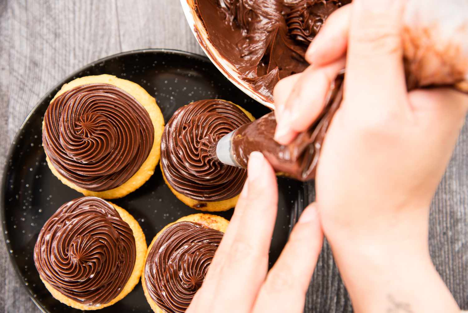 Piping easy chocolate ganache on cupcakes.