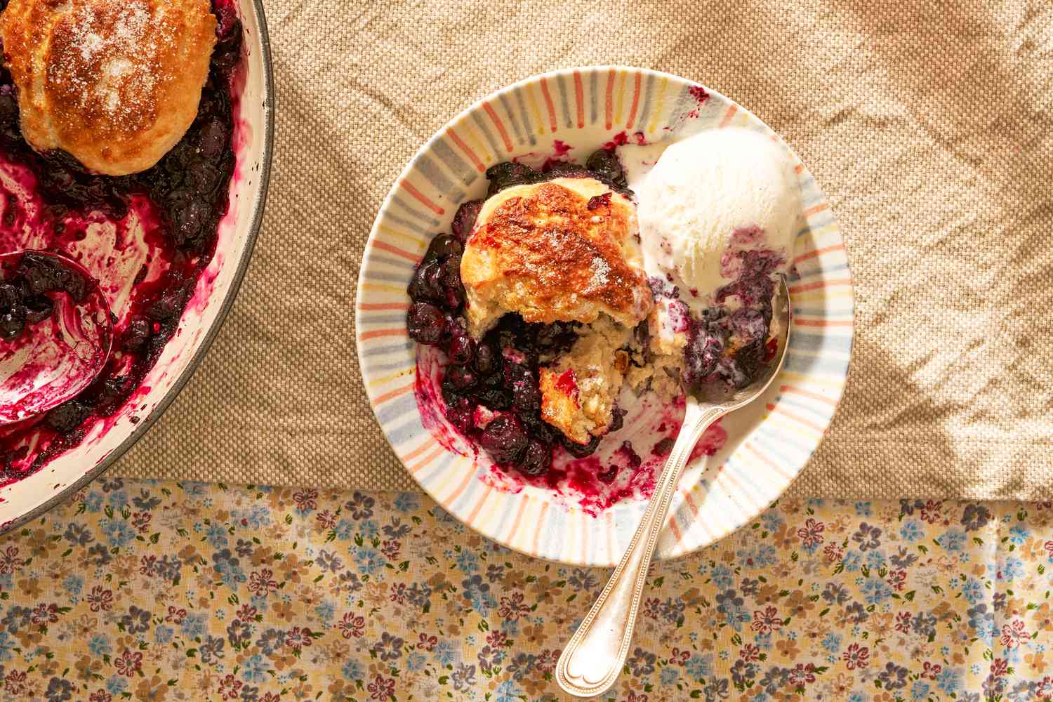 blueberry grunt in a bowl with ice cream next to a baiser with more 
