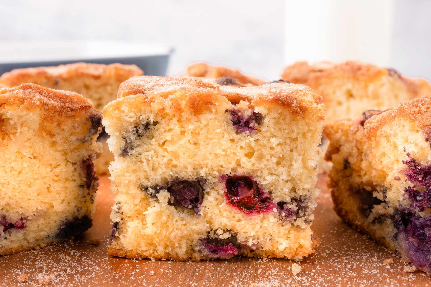 Side view of multiple blueberry coffee cake slices on a wooden cutting board