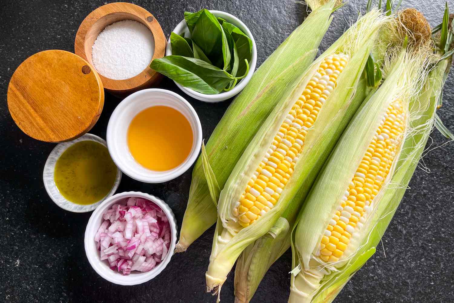 Corn salad ingredients: corn on the cob, red onion, apple cider vinegar, olive oil, basil, and salt