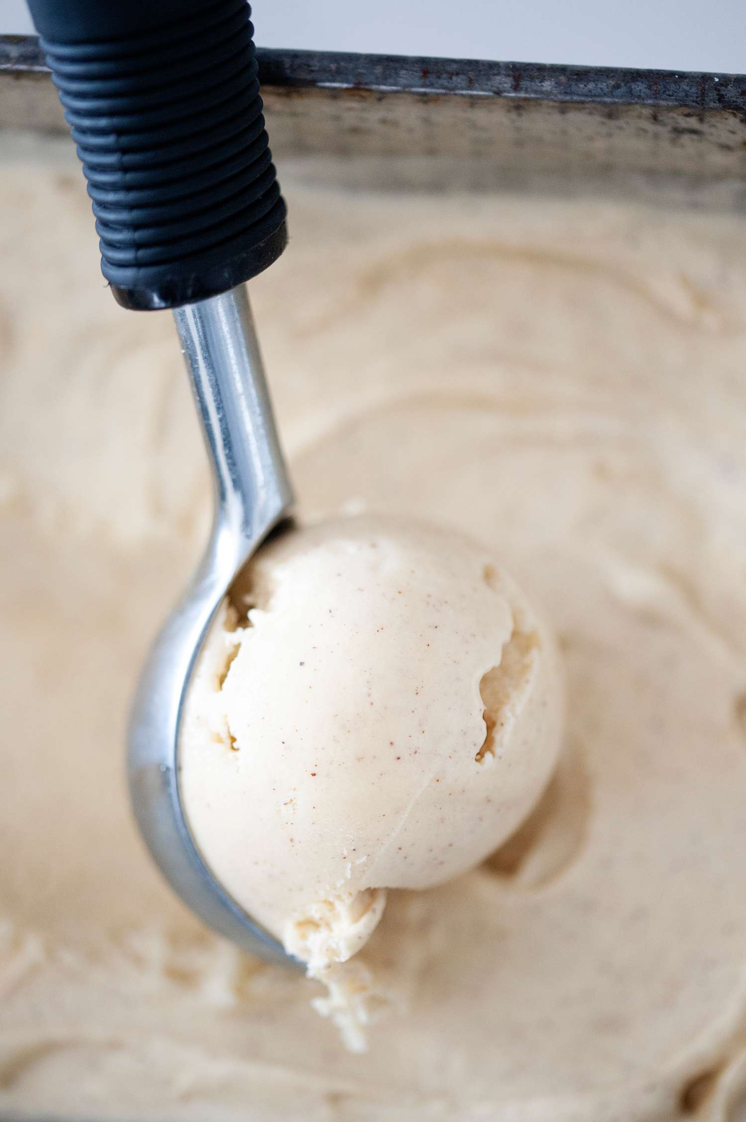 Scooping cinnamon ice cream with an ice cream scoop.