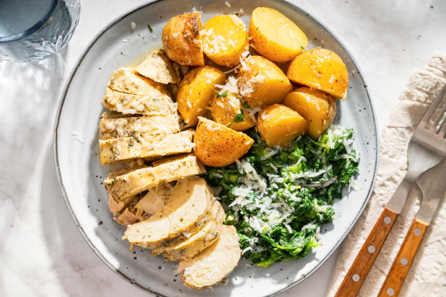 Sliced chicken breast roasted potatoes and sauted greens on a plate