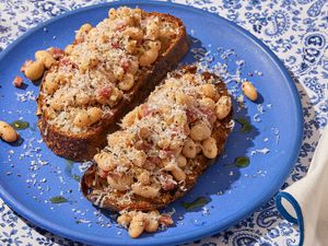 Angled view of a blue plate of two pieces of White Bean and Salami Toasts on a paisley tablecloth