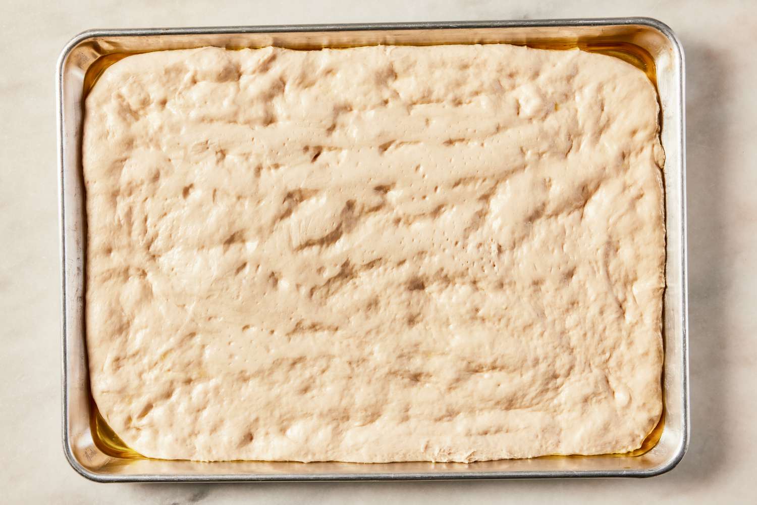 grandma pizza dough in a sheet pan after proofing