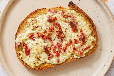 Cottage cheese toast topped with sundried tomatoes on a ceramic plate