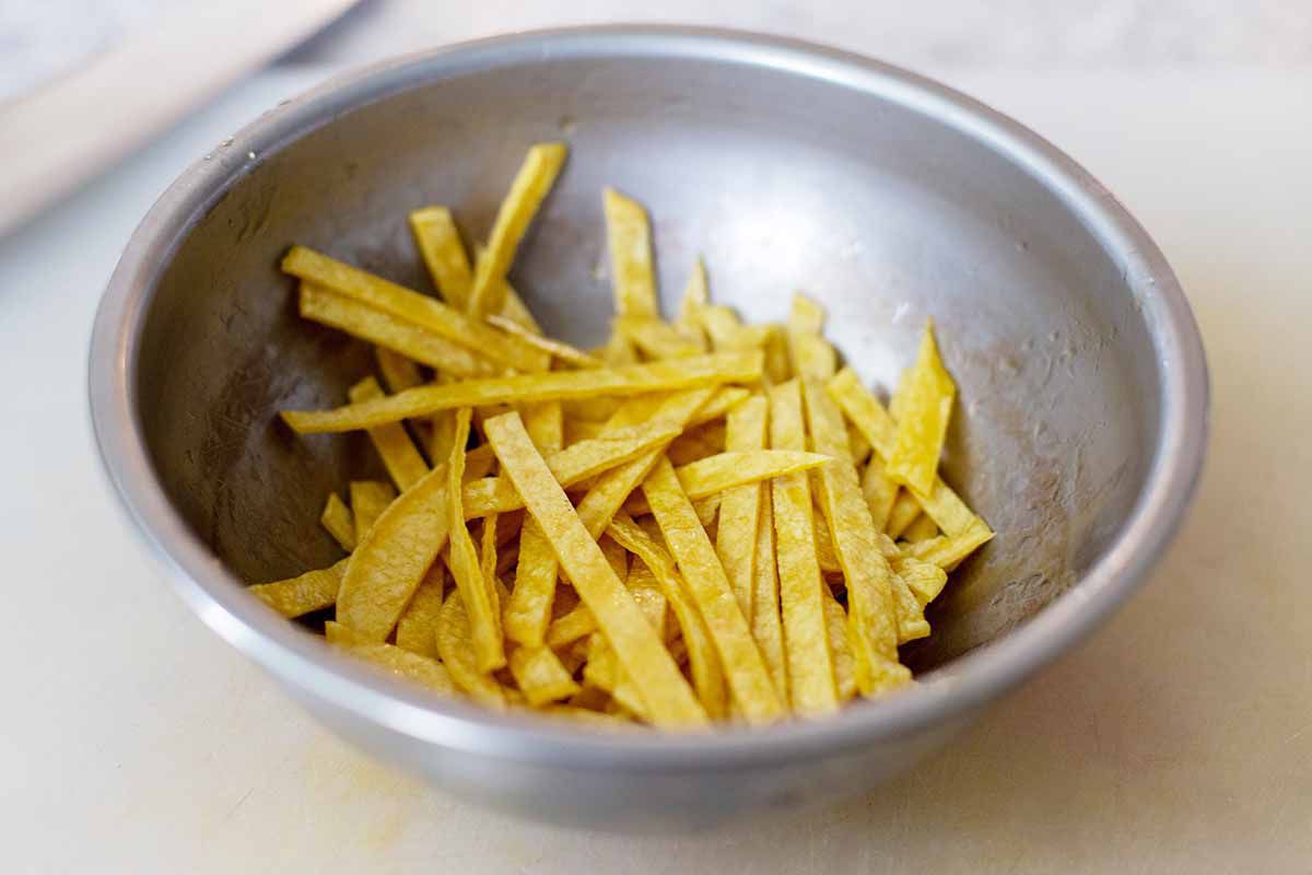 Strips of yellow corn tortillas or in a metal bowl and coated with oil to make easy instant pot chicken tortilla soup.