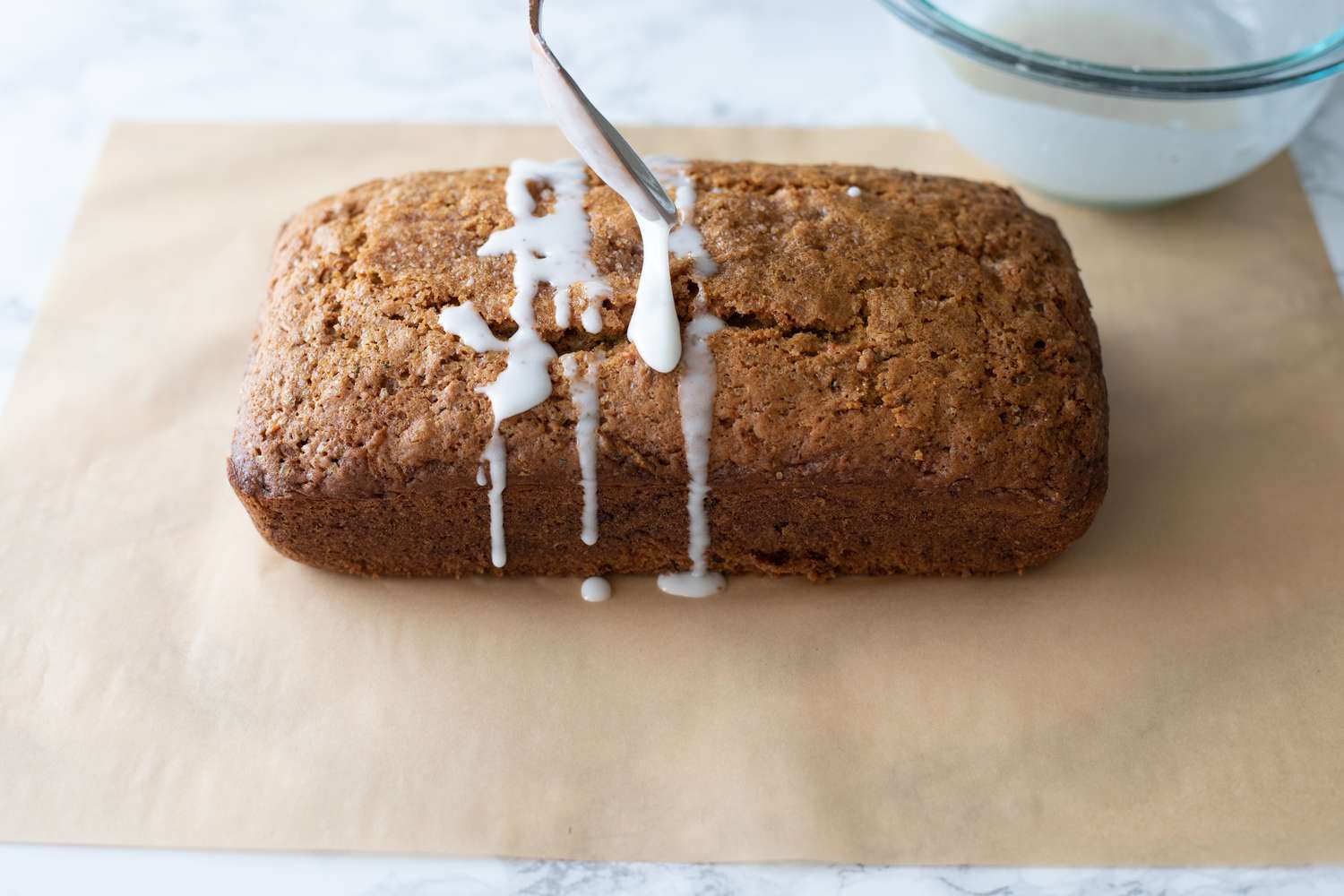 Zucchini Carrot Bread Glazed Using a Spoon over a Piece of Parchment Paper 