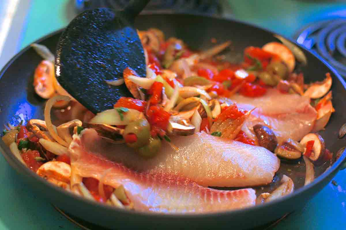 tilapia fillets in pan with tomatoes onions mushrooms
