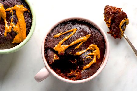 Chocolate peanut butter mug cakes garnished with peanut butter one partially eaten