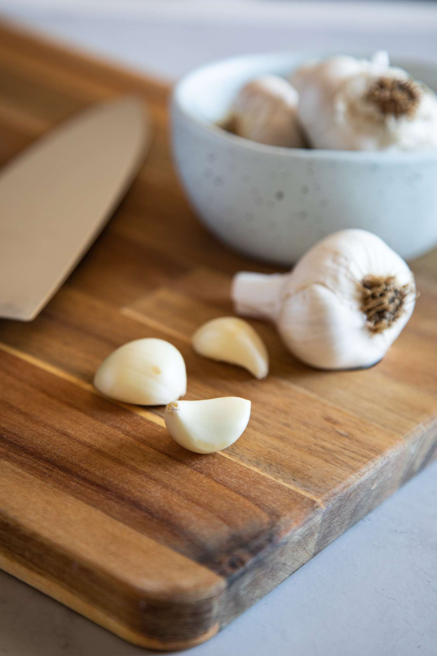 Cloves of garlic and a garlic head on a wood cutting board