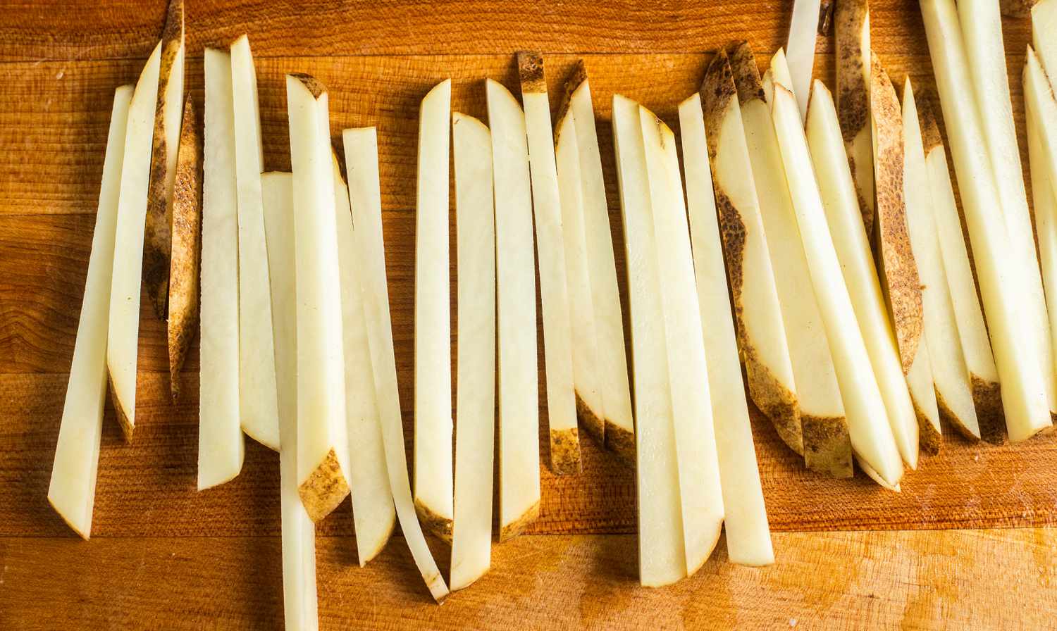 Uncooked Homemade French Fries on Cutting Board 