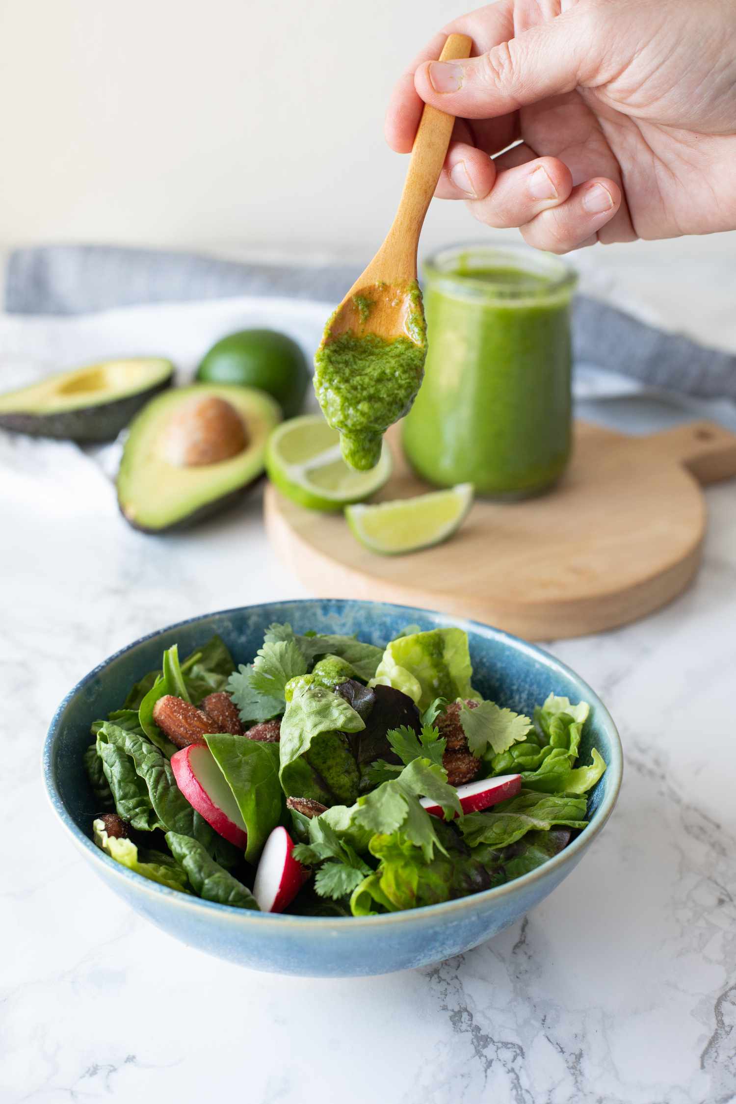 Spoonful of Avocado Lime Dressing and a Bowl of Salad 