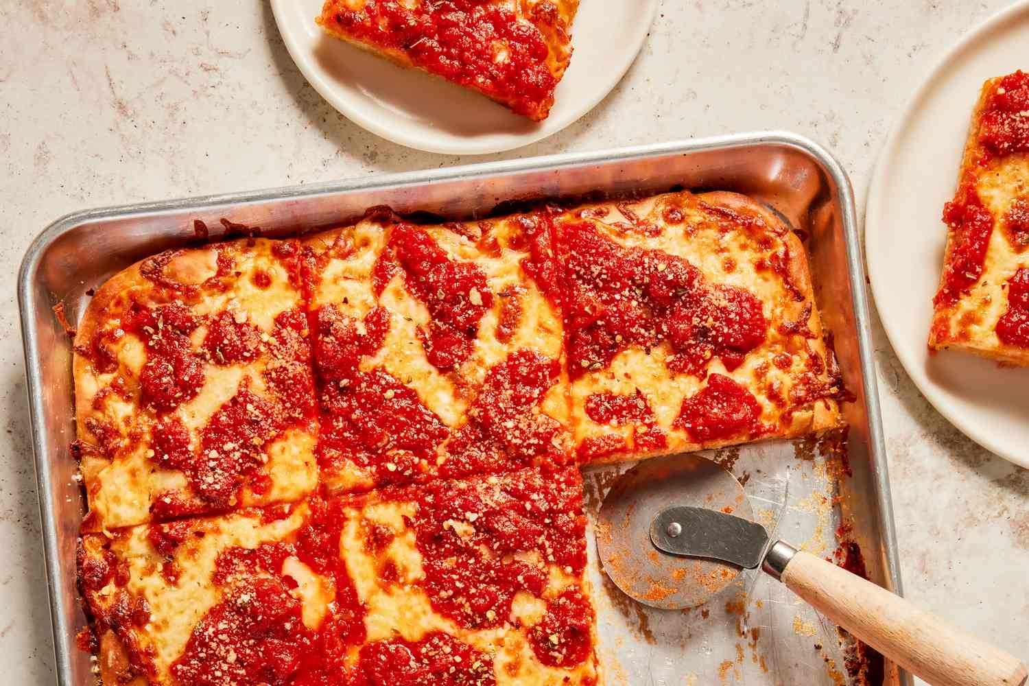 grandma pizza slices in a sheet pan next to slices on two plates