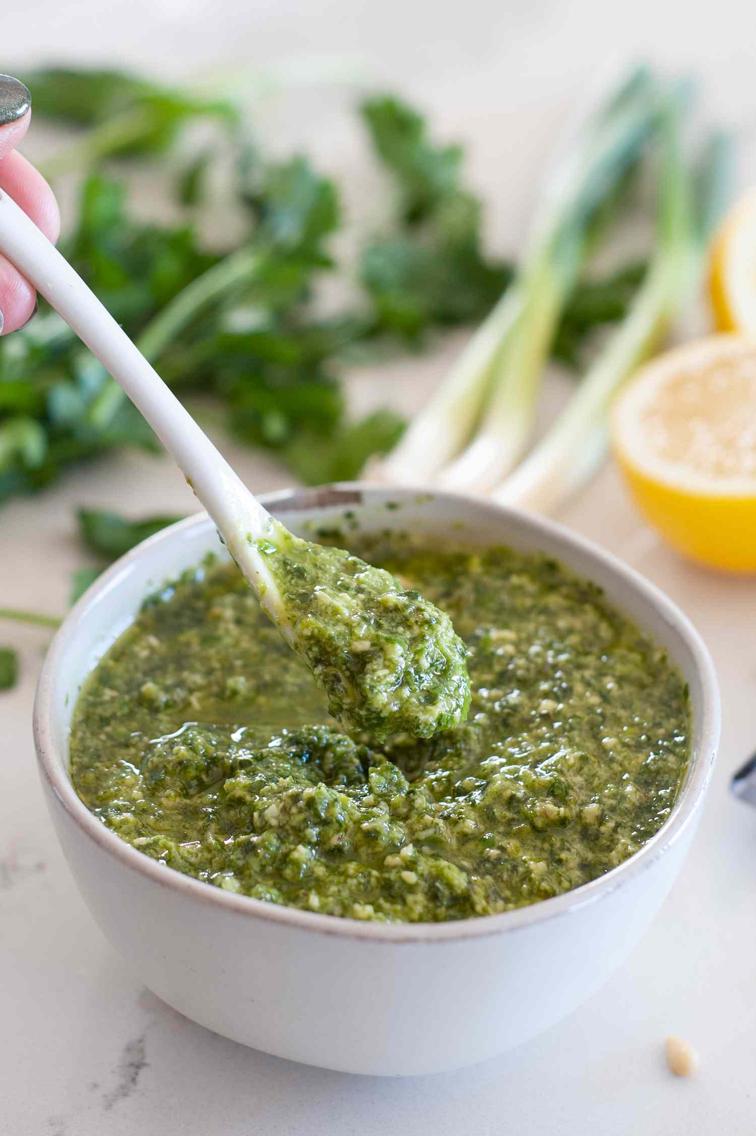 Scallion pesto in white bowl with white spoon