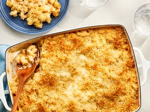 Overhead view of a baking dish of macaroni and cheese topped with panko, a serving spoon in the corner next to a small blue plate with a serving