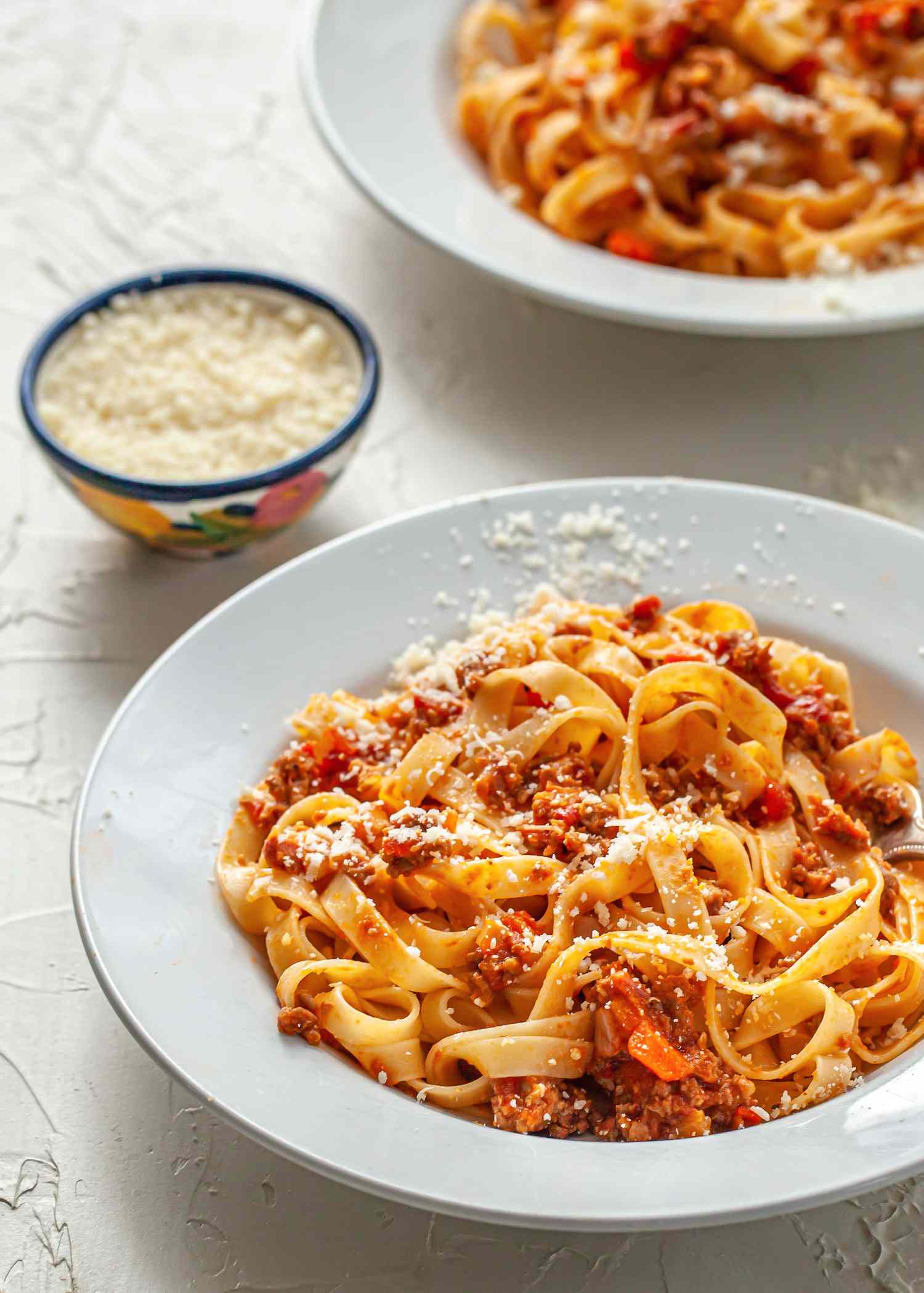 Pasta with bolognese sauce on two white plates.