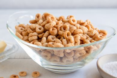 A bowl of fried Cheerios with butter and salt visible in the background