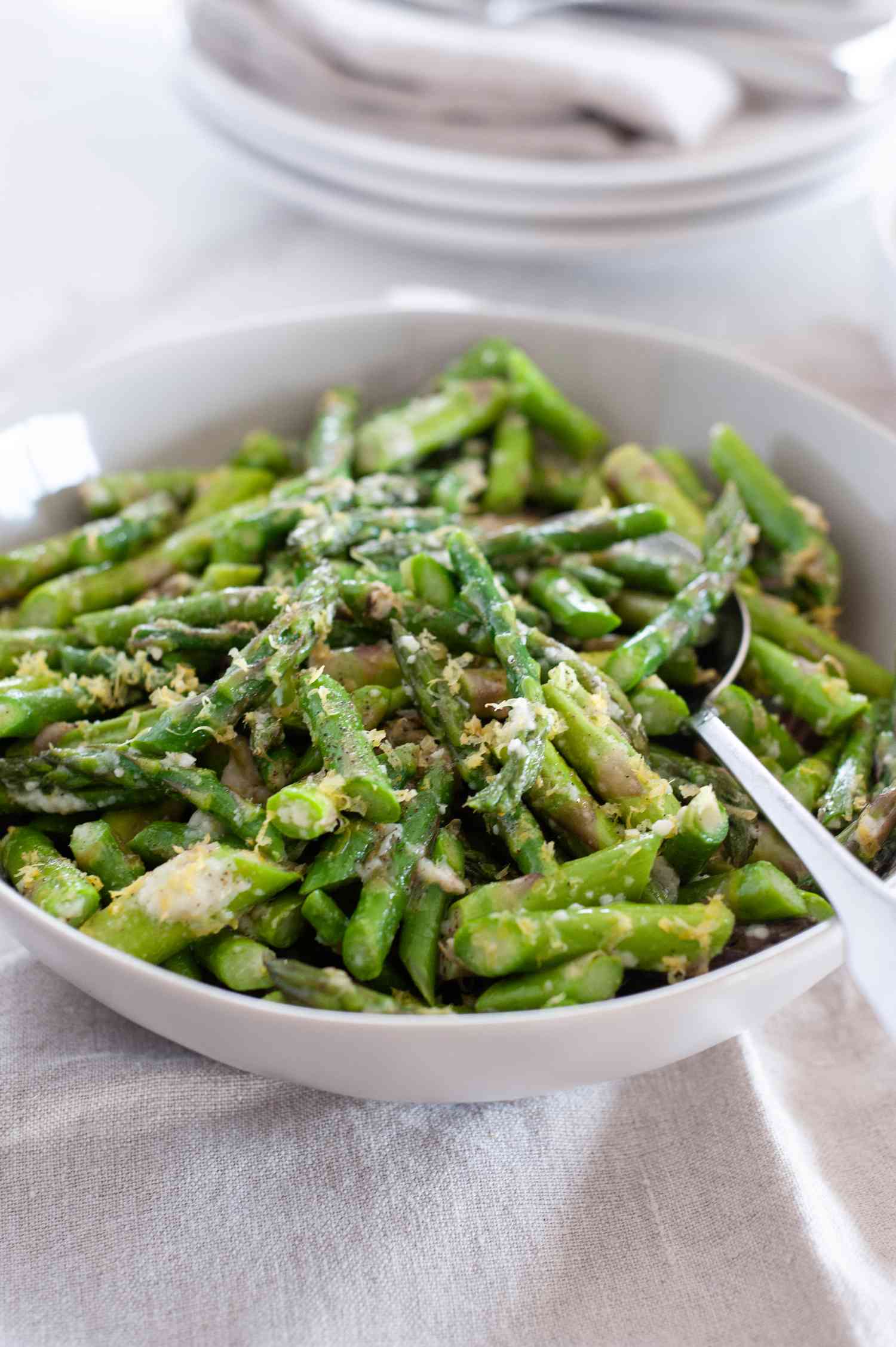 Asparagus with shredded Parmesan in a bowl with a spoon