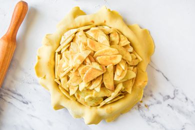 An apple pie before baking, on a marble countertop