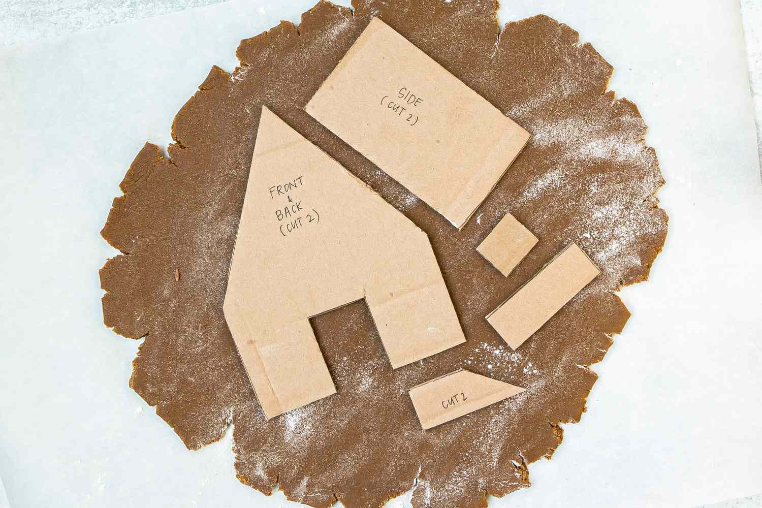 The gingerbread house template laid over gingerbread dough.