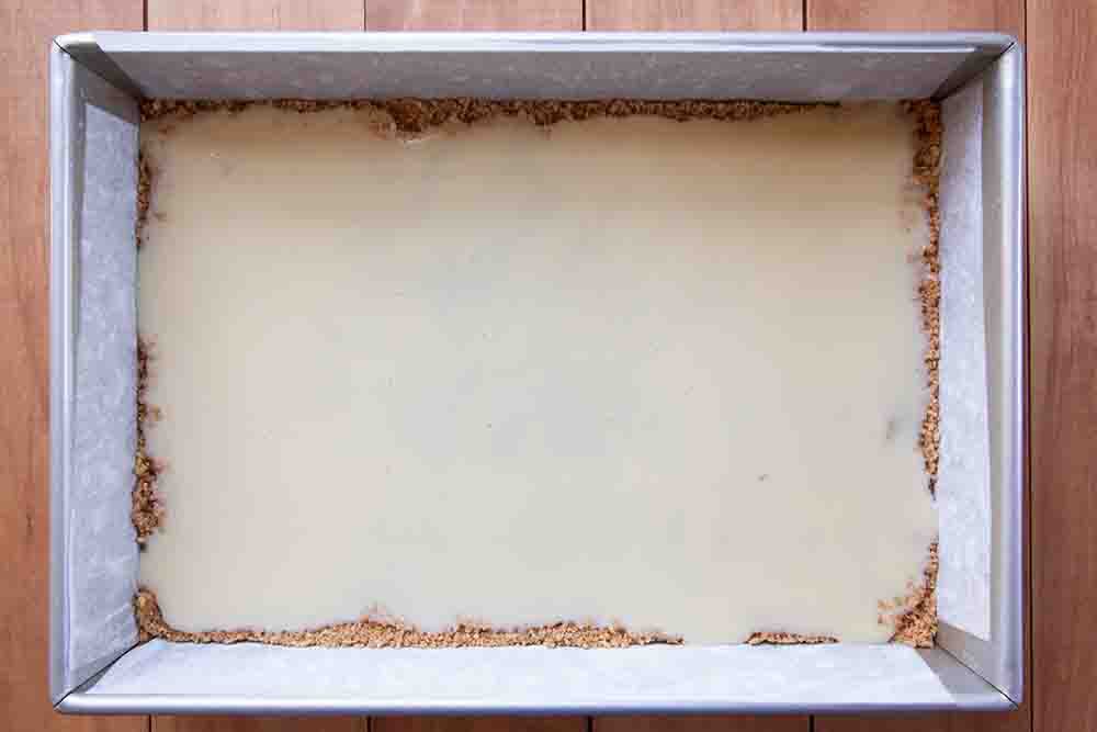 Sweetened condensed milk poured over the graham cracker layer for making 7 layer bars
