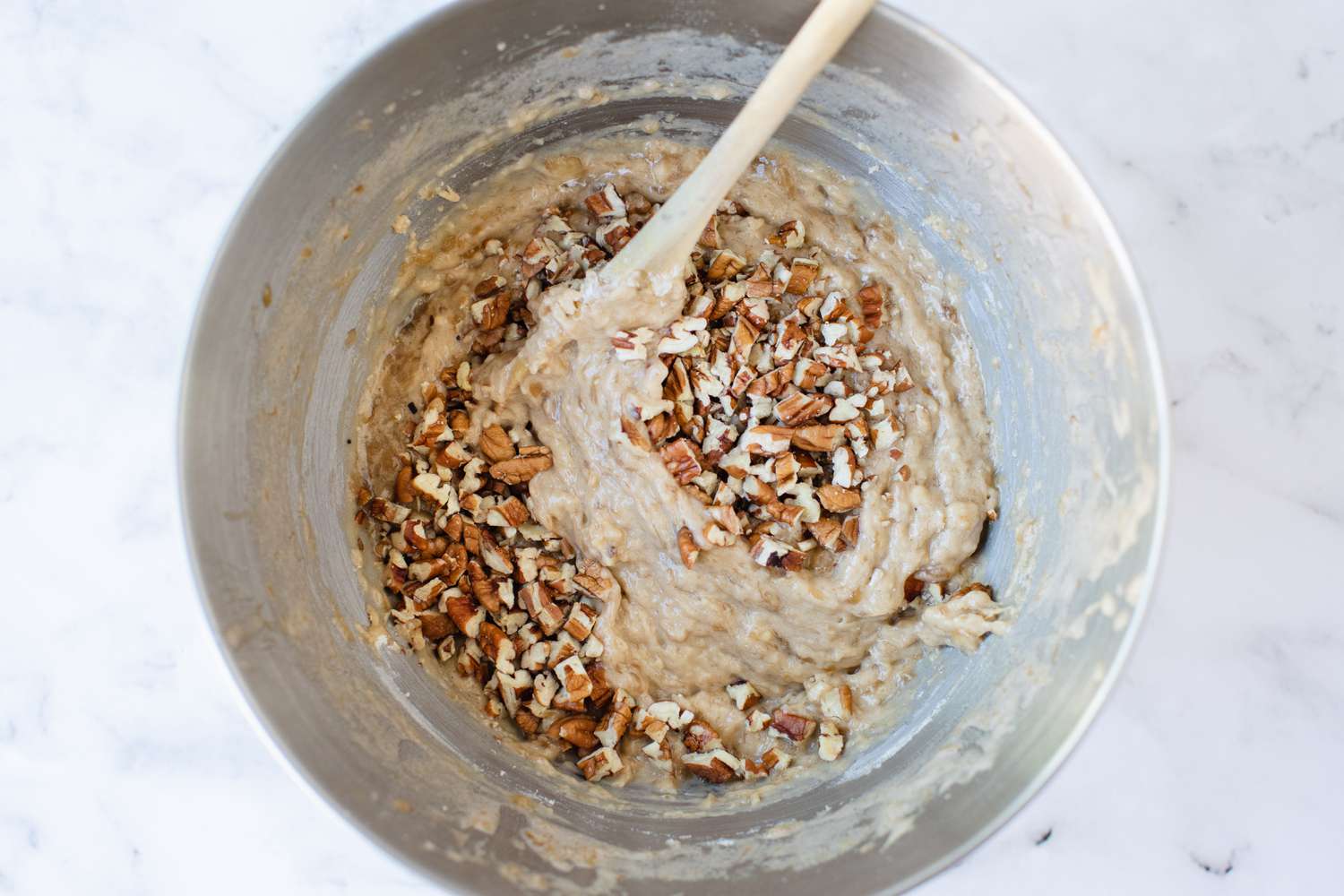 Adding nuts to a bowl of banana muffin batter