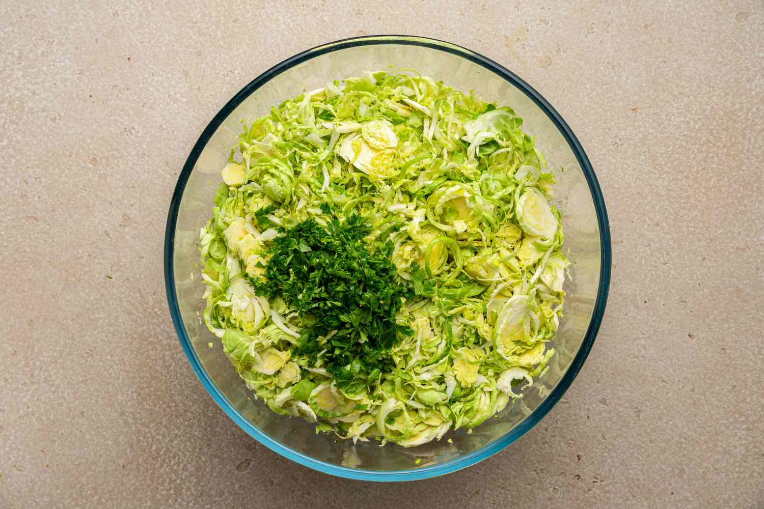 Parsley and and Olive Oil Added to Bowl of Shredded Brussels Sprouts for Caesar Salad
