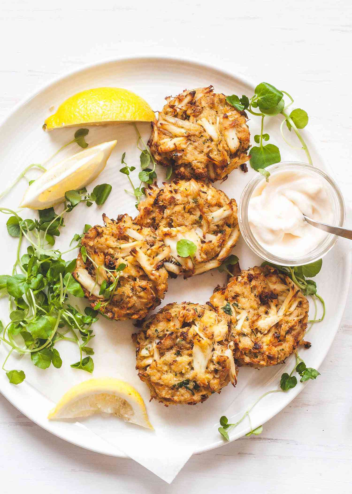 Crab meat on a white plate wtih lemon wedges and mayo dip