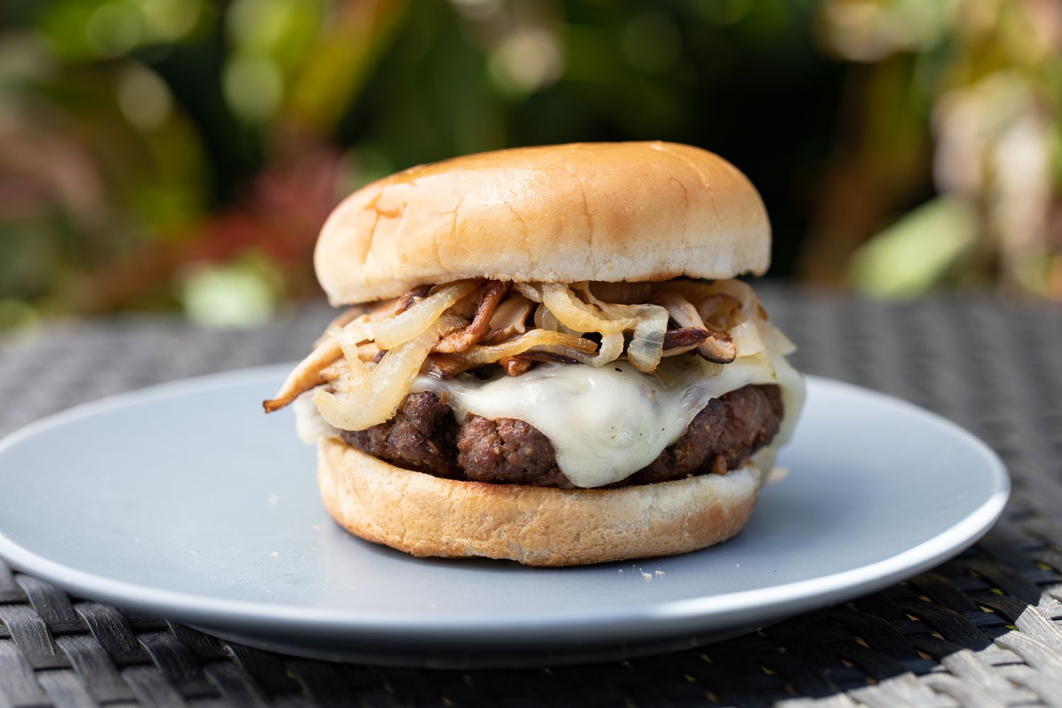 Side view of a mushroom swiss burger on a plate outside.