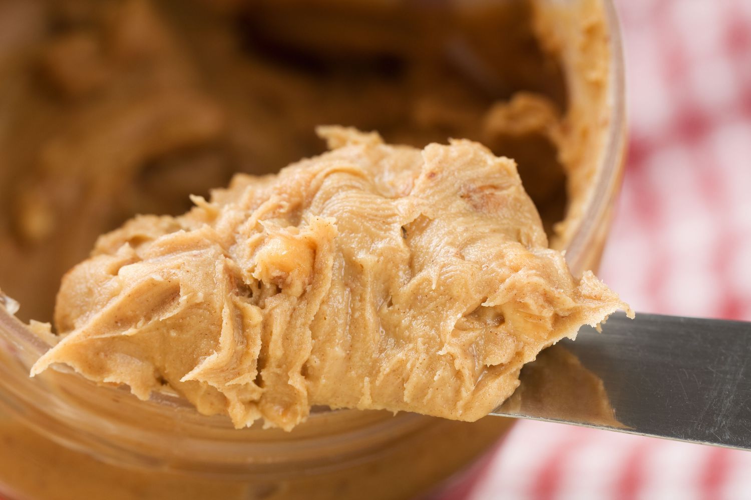 peanut butter on a knife coming out of a jar