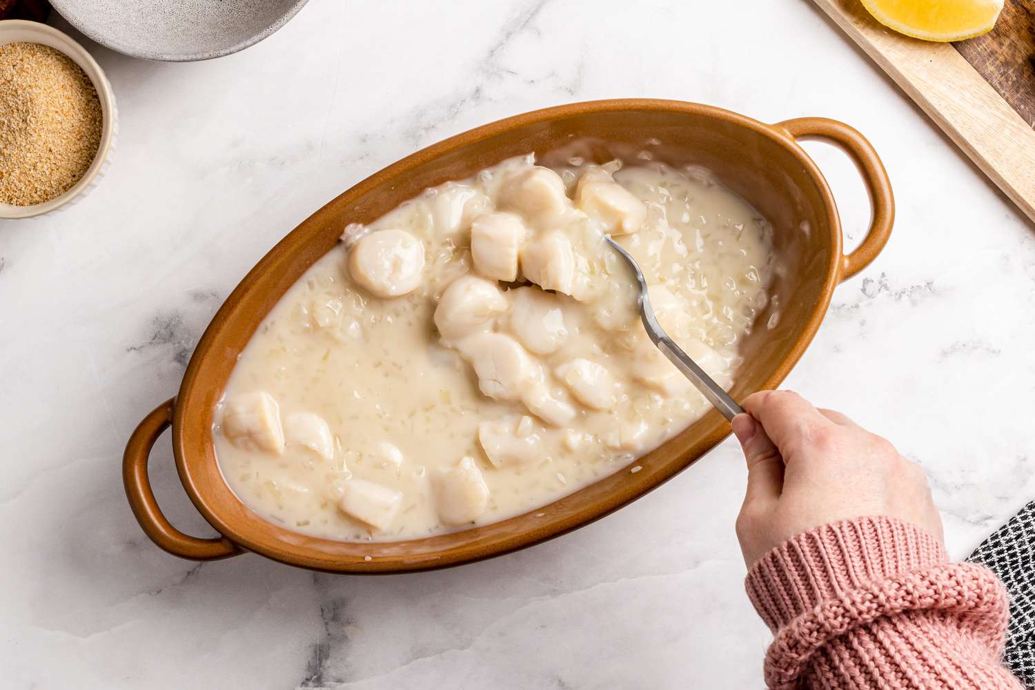 Scallops and a creamy sauce in a baking dish